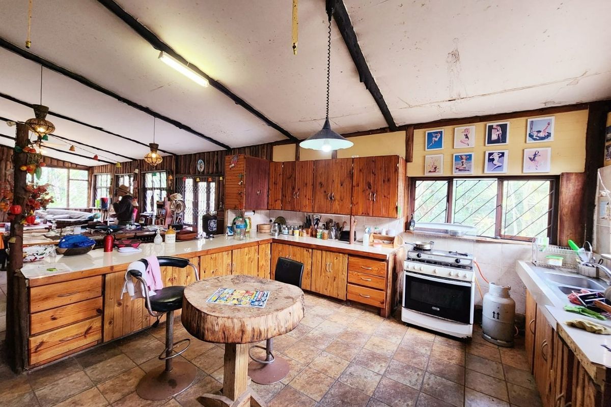 Rustic kitchen featuring wooden cabinetry, gas stove, and tiled flooring with exposed ceiling beams, offering a traditional farm-style aesthetic in need of modernization.