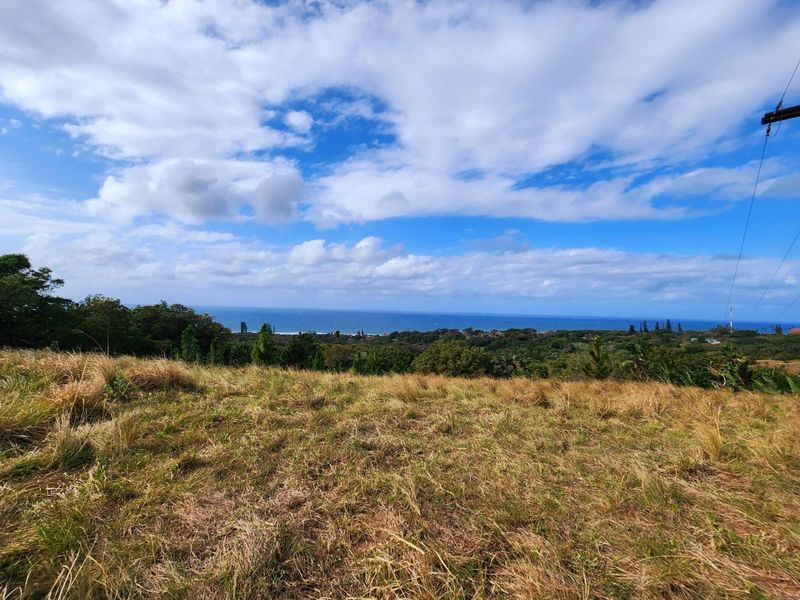 A scenic landscape view overlooking the surrounding countryside and distant coastline under a bright, cloudy sky.