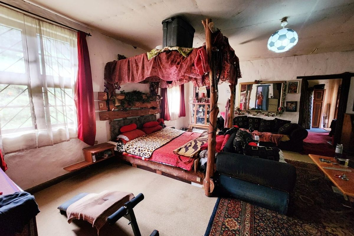 Spacious bedroom featuring built-in shelving and large windows, currently requiring significant cosmetic updates and ceiling repairs to restore its potential.