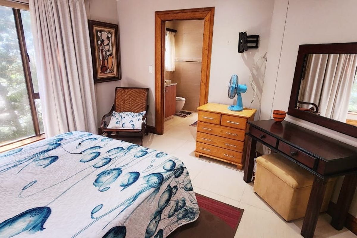A bedroom featuring large windows, tiled flooring, and an en-suite bathroom entrance.