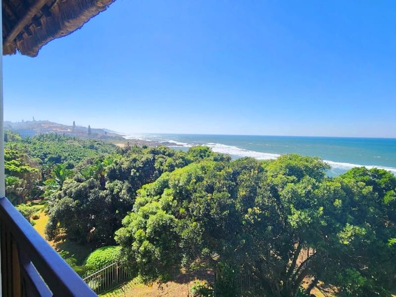 A spacious balcony offering panoramic ocean and coastal views, featuring tiled flooring and a covered area, perfect for outdoor relaxation.