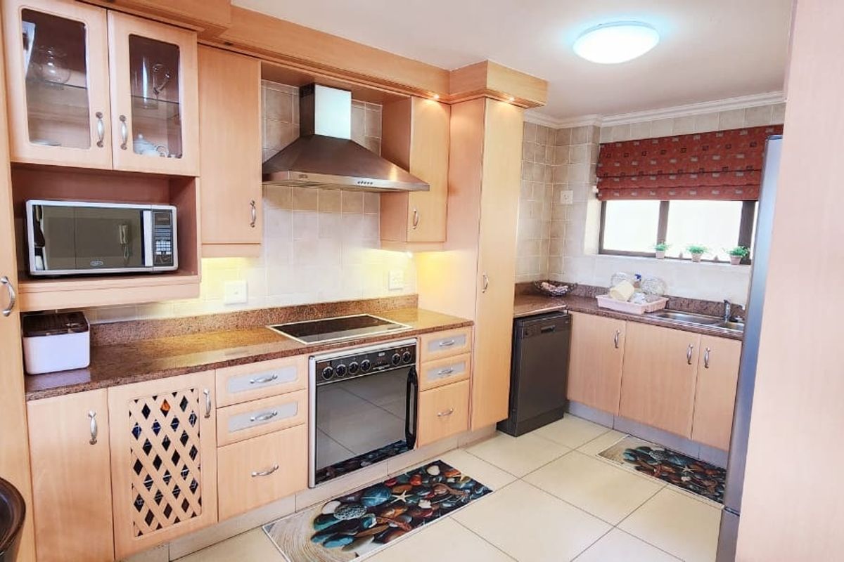 A functional kitchen featuring light wood cabinetry, granite countertops, a built-in oven, extractor fan, and tiled flooring with a practical layout.
