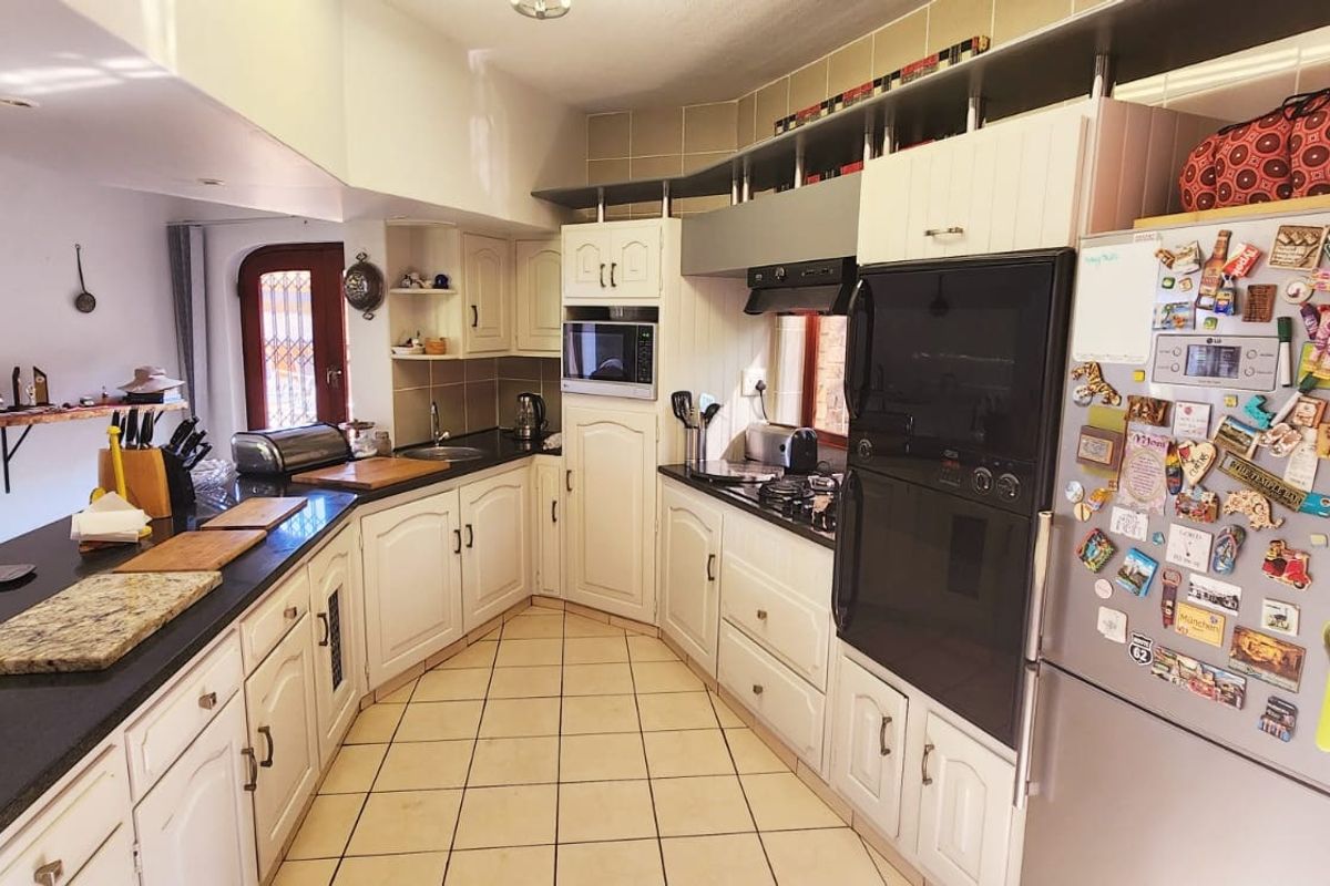 A functional kitchen featuring white cabinetry, granite countertops, built-in appliances, and tiled flooring, offering a practical layout for daily cooking and meal preparation.