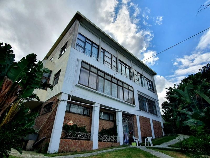 Rear view of a multi-story apartment building featuring stone cladding, large windows, and a paved garden walkway.
