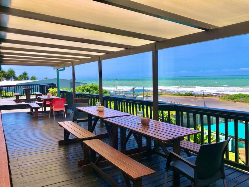 Spacious elevated timber deck featuring a covered pergola and panoramic ocean views, ideal for outdoor entertaining.