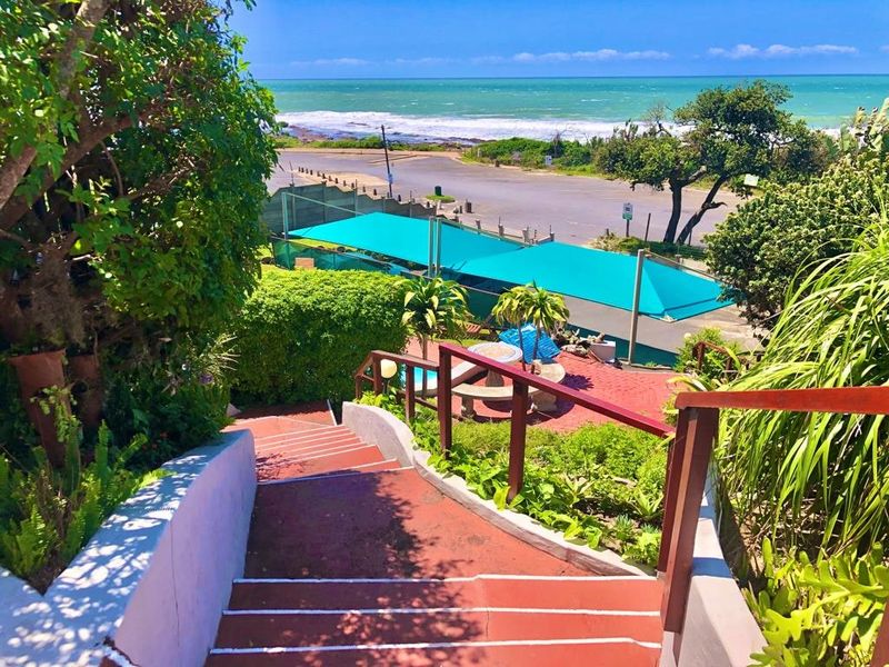Elevated outdoor view overlooking a swimming pool, garden area, and coastal landscape with ocean views.