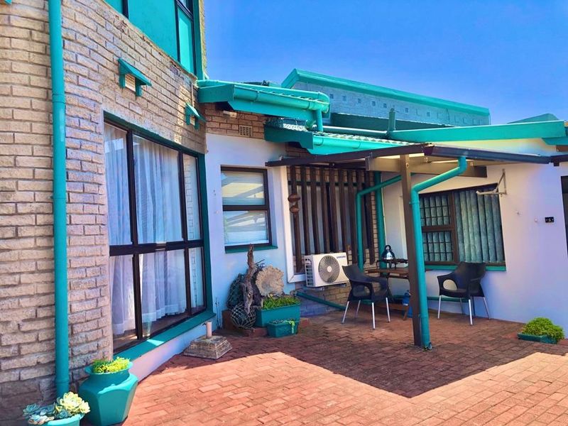 A paved outdoor patio area featuring a covered section, brick exterior walls, and an installed air conditioning unit.