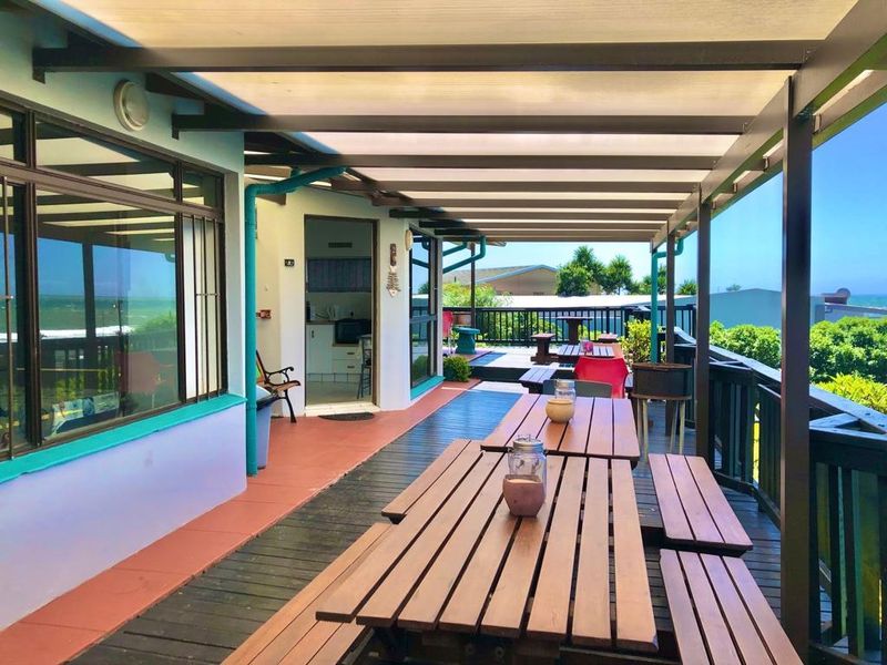 Spacious covered patio featuring timber decking and railing, offering an outdoor entertainment area with views and direct access to the home's interior.