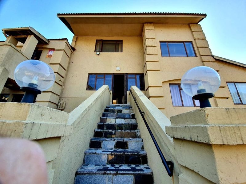 Front elevation of a multi-story residence featuring a prominent stone-tiled staircase leading to the main entrance with exterior globe lighting.