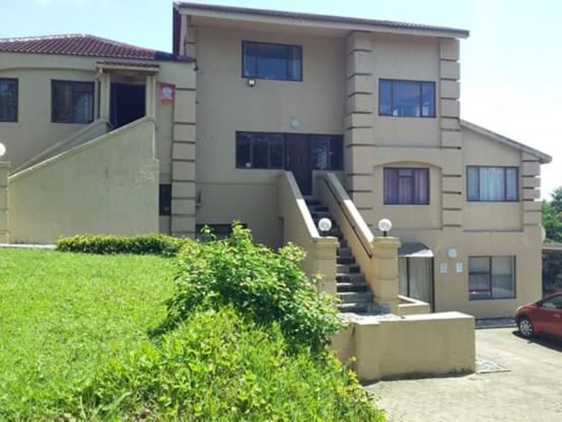 Front elevation of a multi-story residential property featuring a paved driveway, external staircase, and tiled roof.