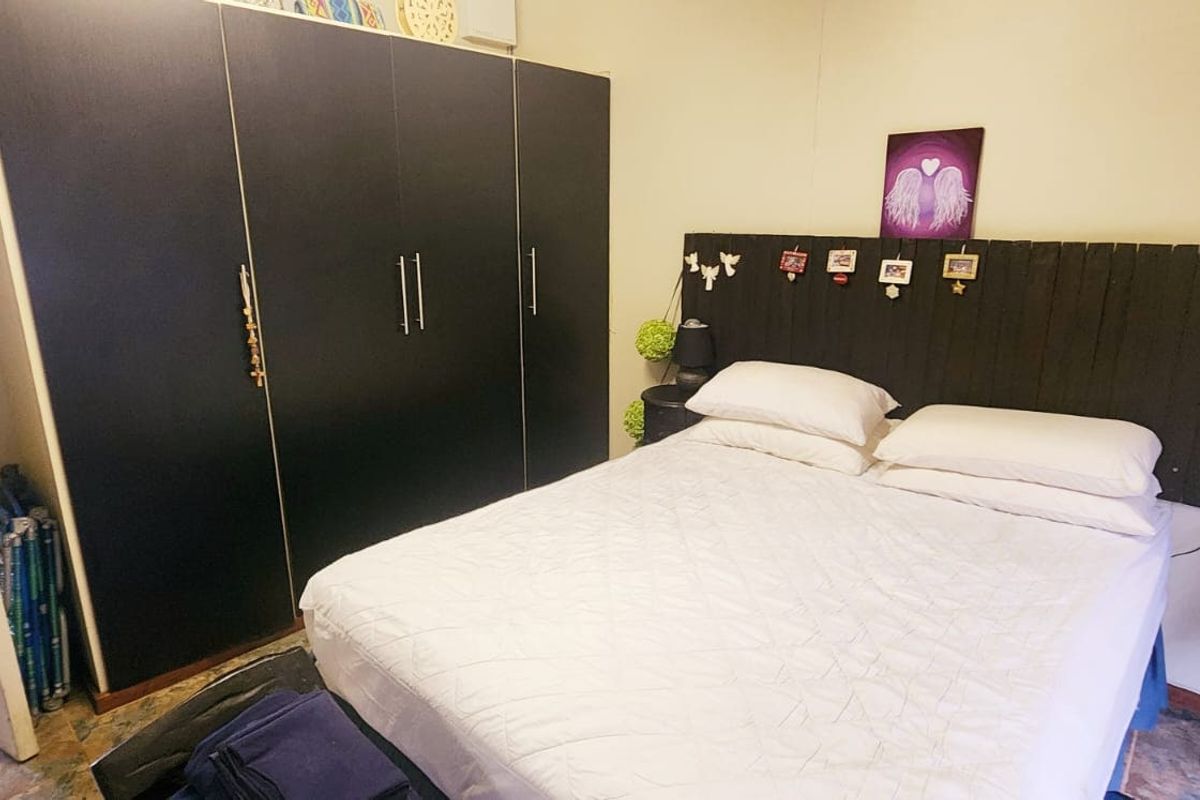 A bedroom featuring a large dark built-in wardrobe and a custom timber headboard.