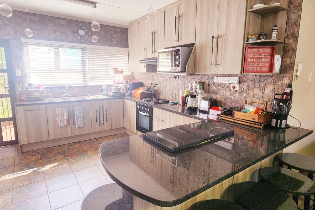 A functional kitchen featuring wood-look cabinetry, granite countertops, a breakfast bar, and built-in appliances, with direct access to the exterior.