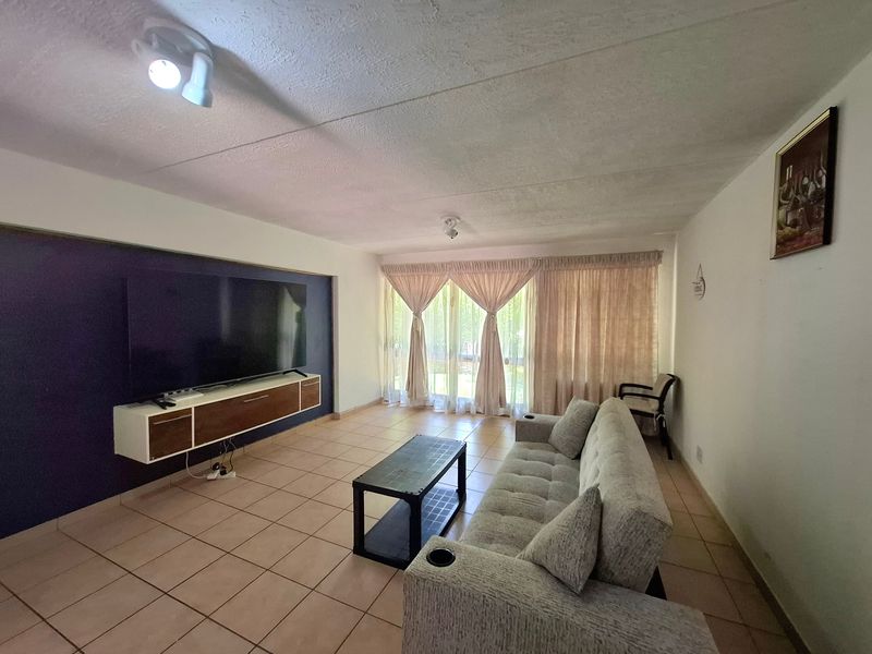 Spacious living room featuring ceramic tile flooring, a dark accent wall, and large sliding glass doors providing natural light.