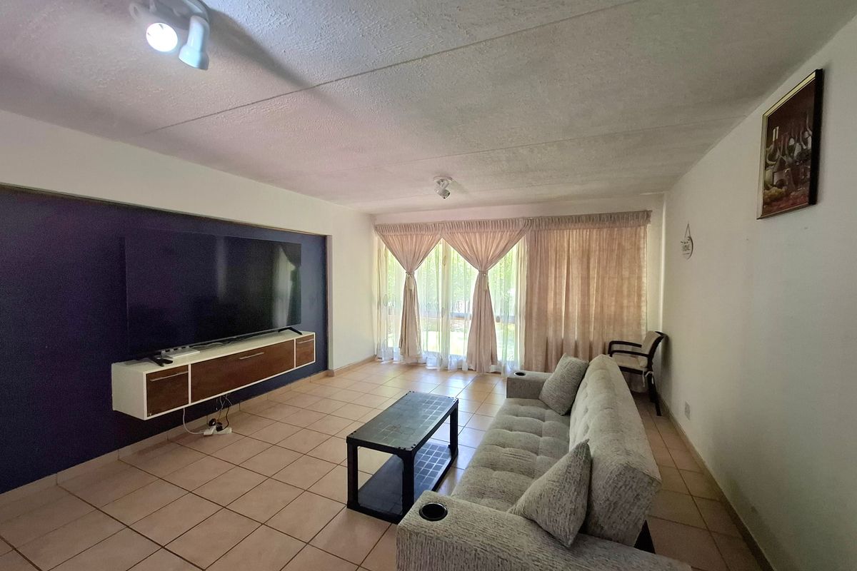 Spacious living room featuring ceramic tile flooring, a dark accent wall, and large sliding glass doors providing natural light.