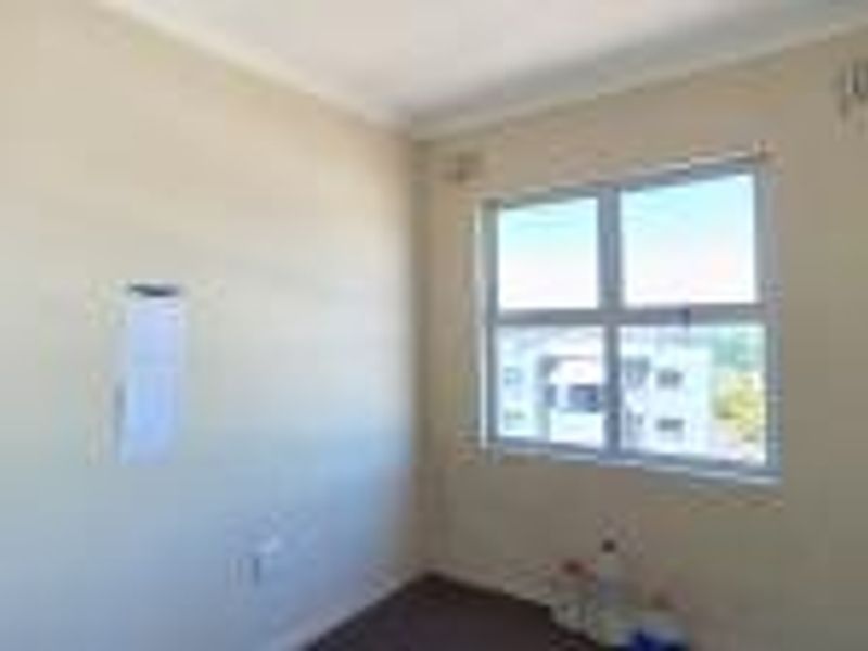 An empty bedroom featuring neutral walls, cove cornicing, and an aluminium-framed window with natural light.