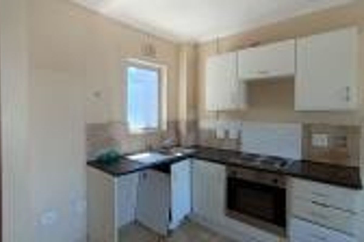A compact kitchen featuring built-in cabinetry, a stainless steel sink, and an integrated oven with hob, requiring minor repairs to cabinetry.