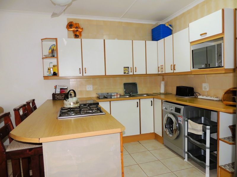 Functional kitchen featuring laminate countertops, built-in cabinetry, a gas hob, and tiled finishes, offering a practical layout for daily meal preparation.