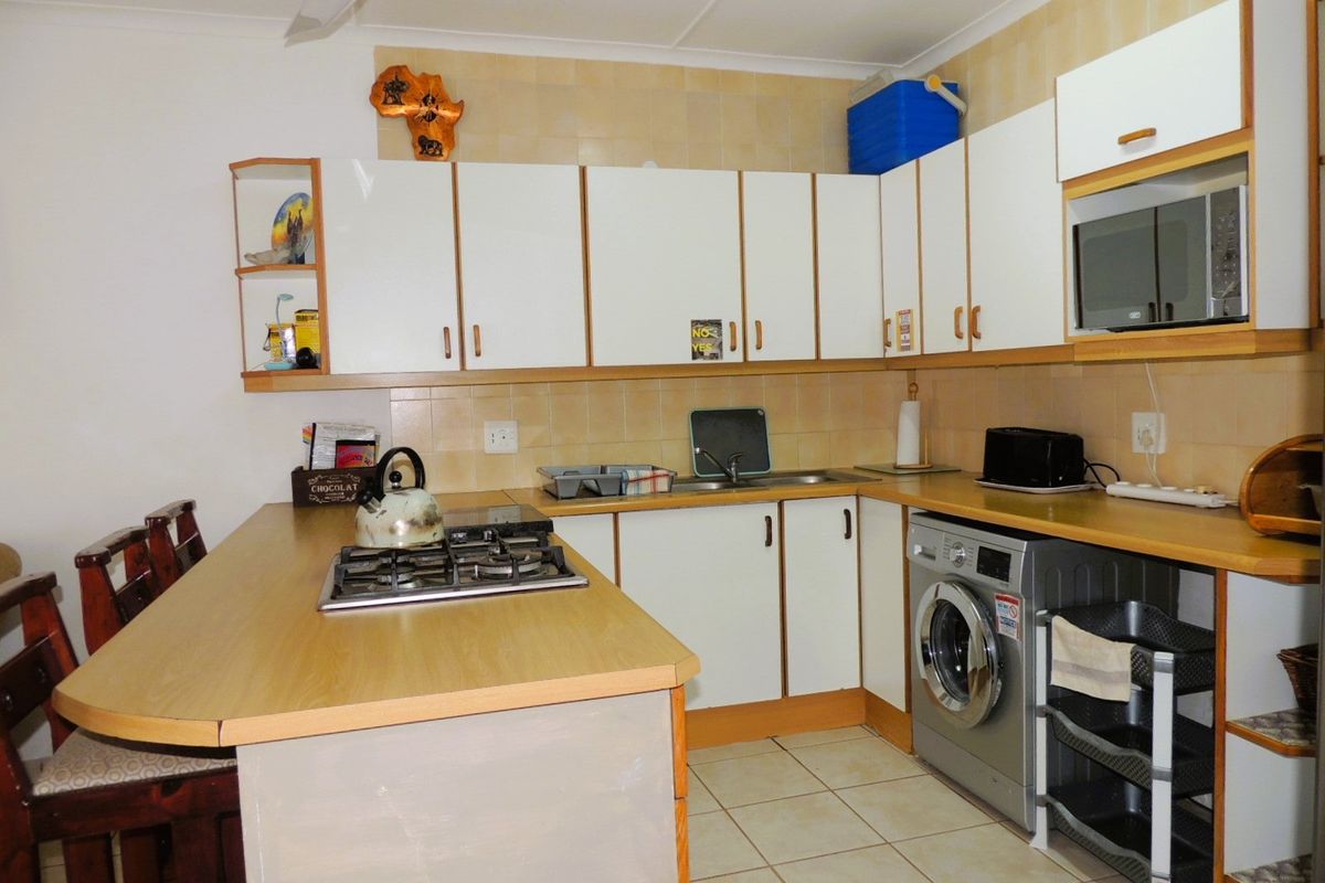 Functional kitchen featuring laminate countertops, built-in cabinetry, a gas hob, and tiled finishes, offering a practical layout for daily meal preparation.
