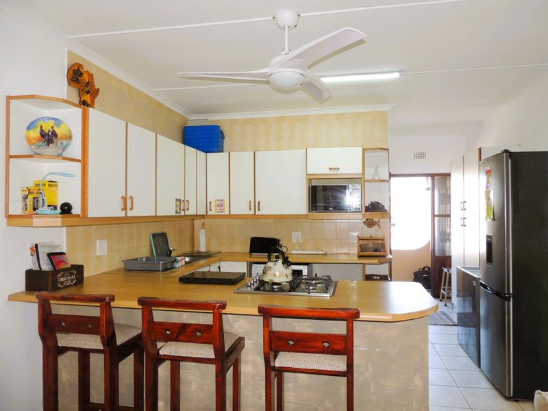 Functional kitchen featuring built-in cabinetry, laminate countertops, a gas hob, and a tiled backsplash, offering a practical layout for daily cooking.