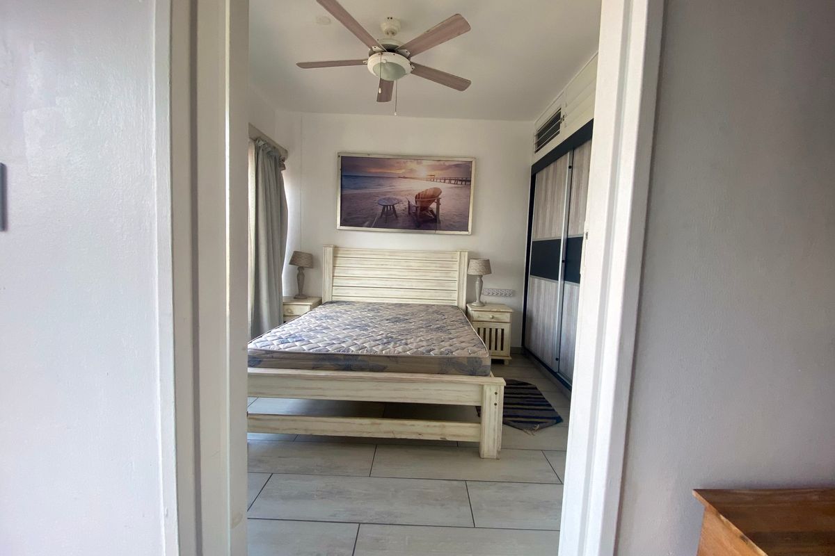 A bedroom featuring tiled flooring, a ceiling fan, an air conditioning unit, and built-in wardrobe storage.