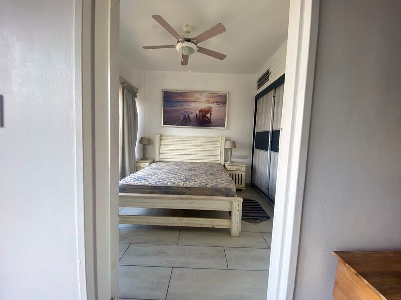 A bedroom featuring tiled flooring, a ceiling fan, an air conditioning unit, and built-in wardrobe storage.