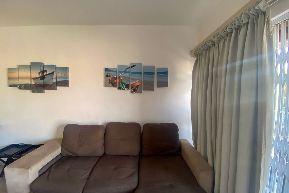A living room area featuring a sliding door with a security gate and neutral wall finishes.