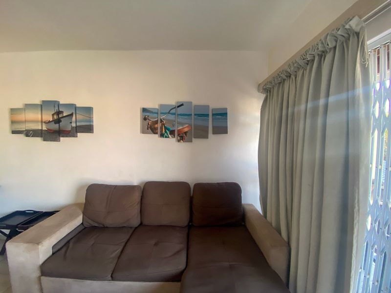 A living room area featuring a sliding door with a security gate and neutral wall finishes.