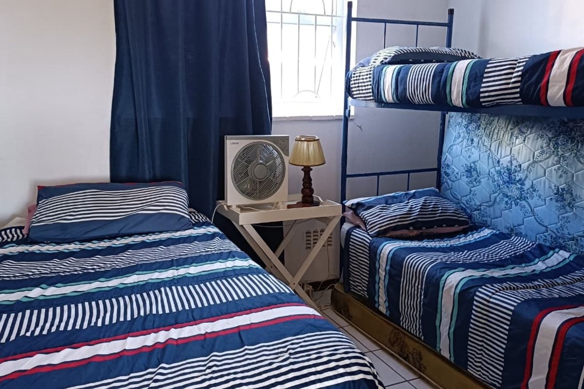 A compact bedroom featuring tiled flooring and a window fitted with security bars.