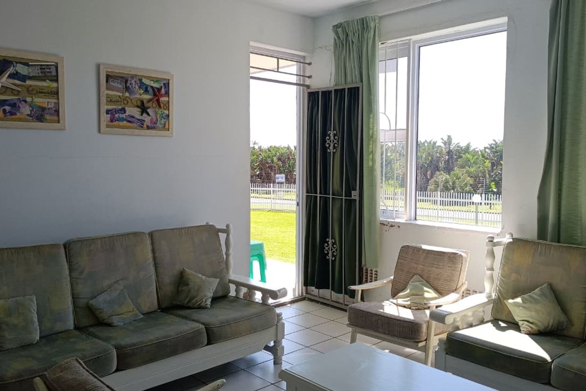 A bright living room featuring tiled floors and large windows with direct access to an outdoor area, offering a functional and well-lit space.