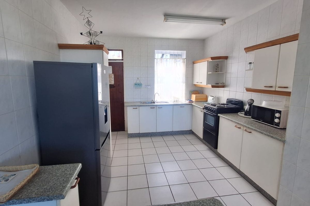 A functional kitchen featuring white cabinetry, granite countertops, tiled walls, and a freestanding stove, offering a clean and practical workspace.