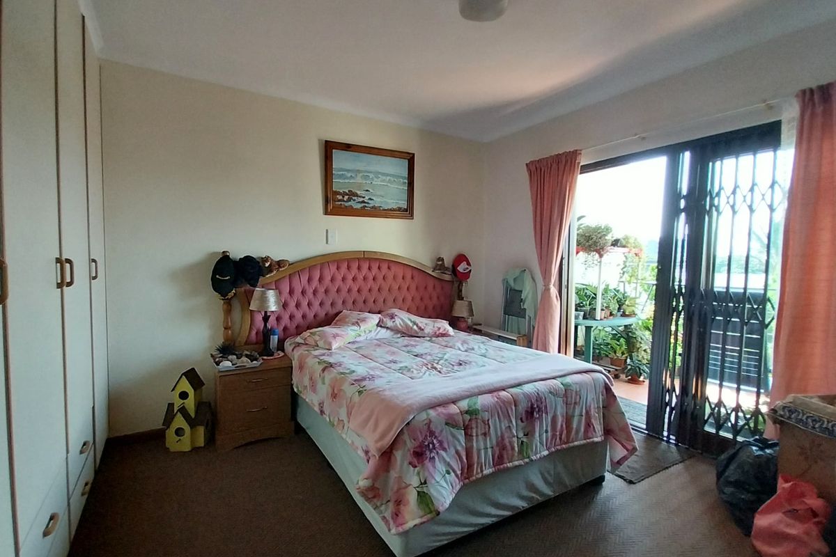 A bedroom featuring built-in cupboards and a sliding glass door with a security gate leading to an outdoor balcony area.
