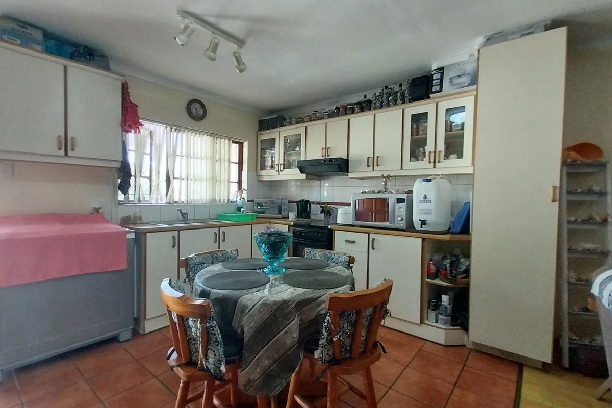 A functional kitchen featuring built-in cabinetry, tiled flooring, and a double sink, offering a practical layout with potential for modern updates.