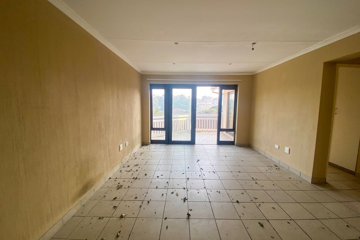 An empty, open-plan living area featuring tiled floors and large sliding glass doors leading to an outdoor balcony space.