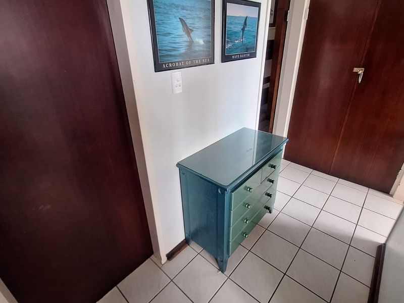 A functional hallway featuring tiled flooring and solid core doors, providing access to adjacent rooms within the apartment.