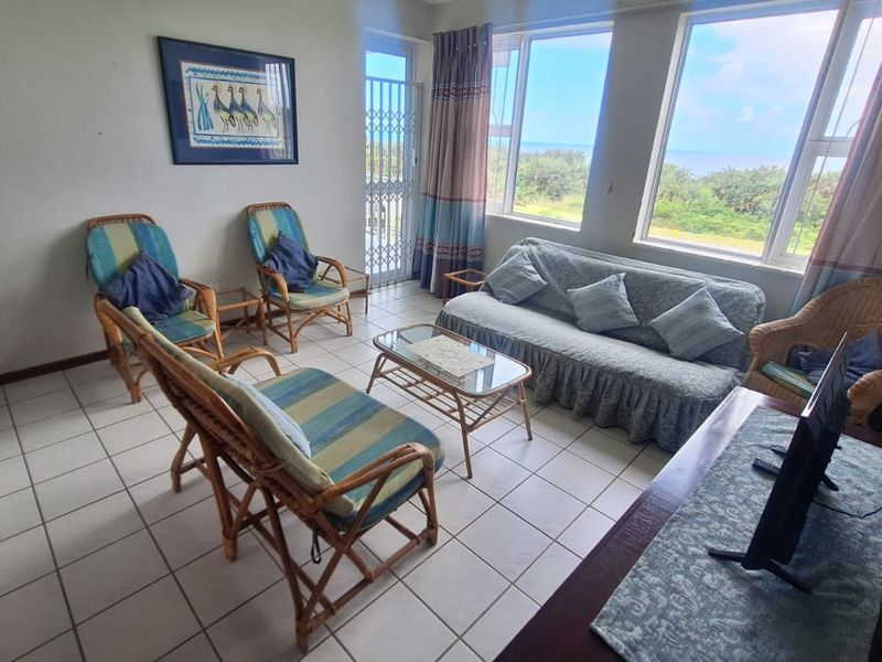 A bright living room featuring tiled flooring and large windows with scenic views, providing a comfortable space for relaxation.