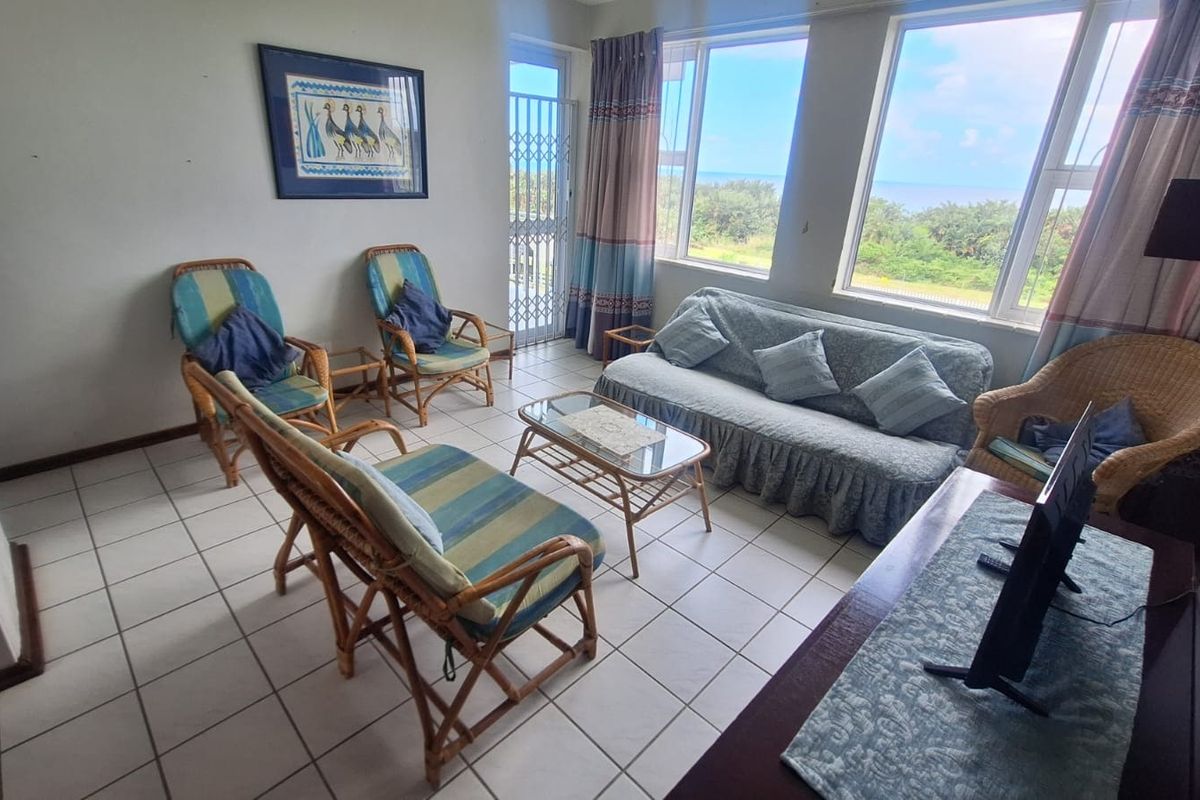 A bright living room featuring tiled flooring and large windows with scenic views, providing a comfortable space for relaxation.