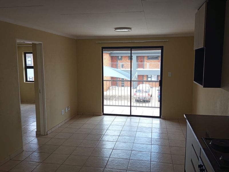 An open-plan living and kitchen area featuring tiled flooring, built-in cabinetry, and a sliding glass door leading to an exterior balcony.