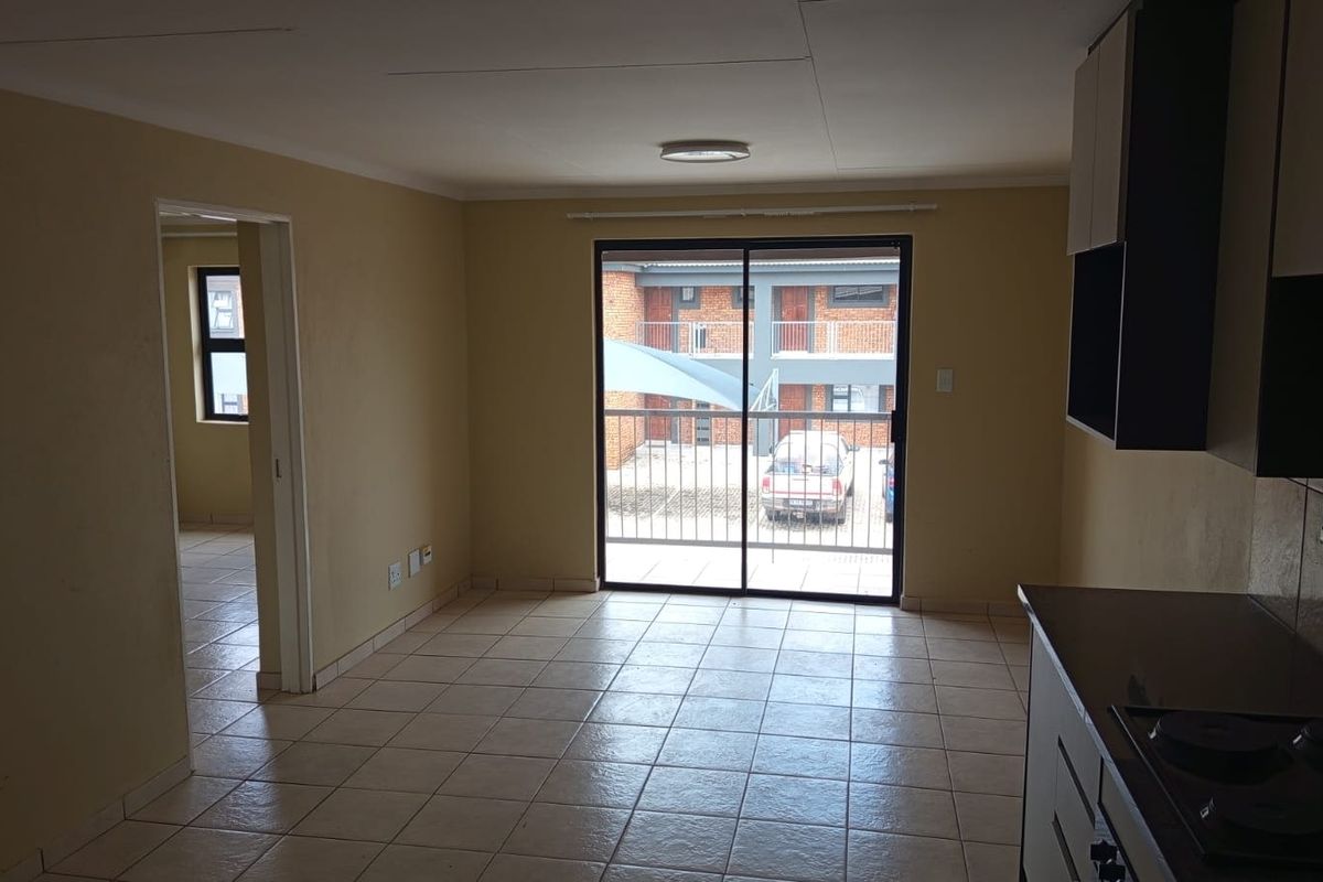 An open-plan living and kitchen area featuring tiled flooring, built-in cabinetry, and a sliding glass door leading to an exterior balcony.