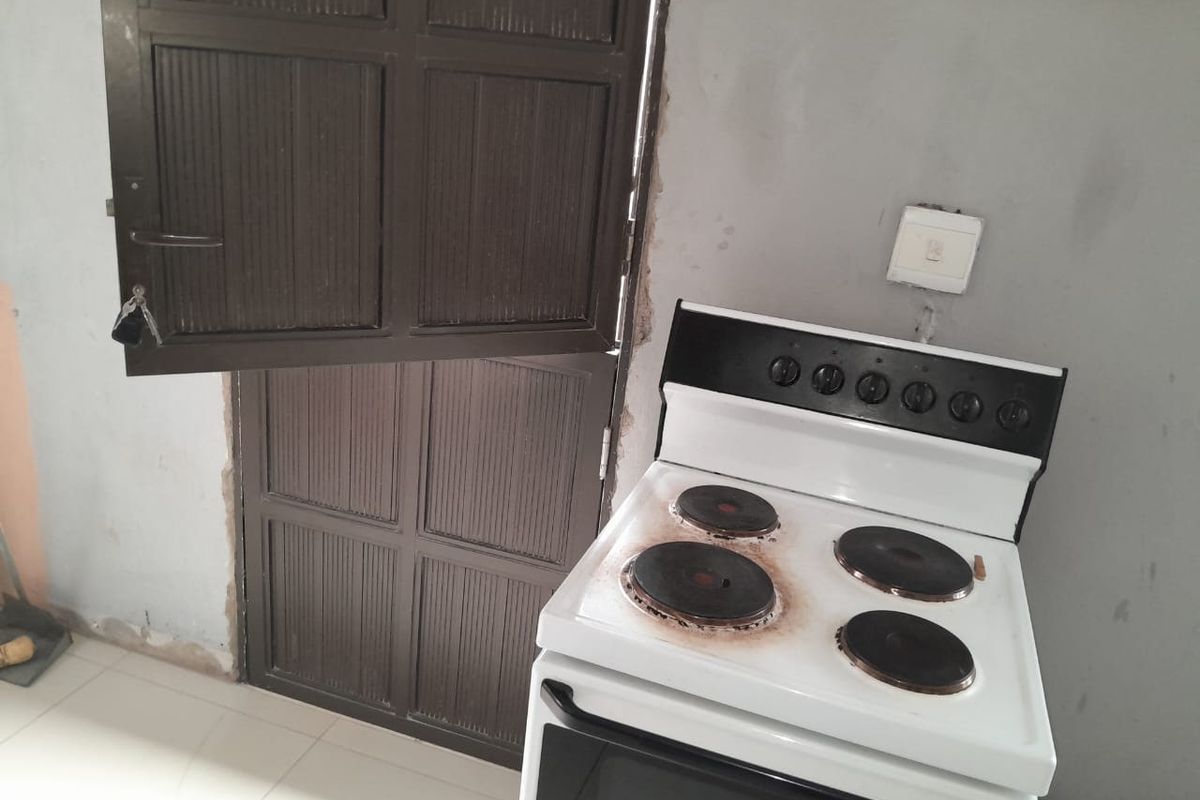 A basic kitchen area featuring a freestanding electric stove and a traditional stable-style door, requiring cosmetic updates to the wall finishes.
