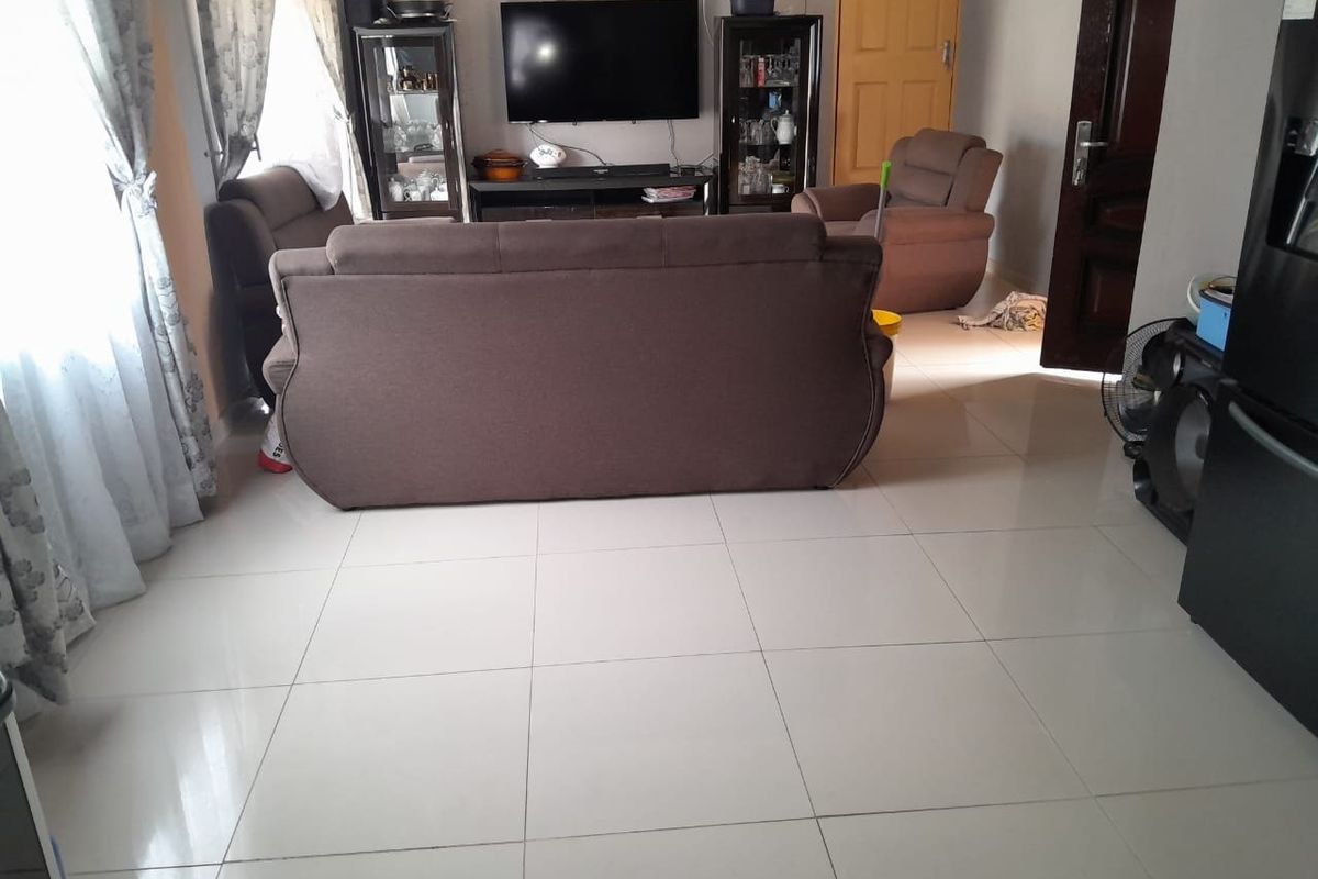 A living room featuring large format porcelain floor tiles and a neutral wall finish, providing a functional and well-lit space.