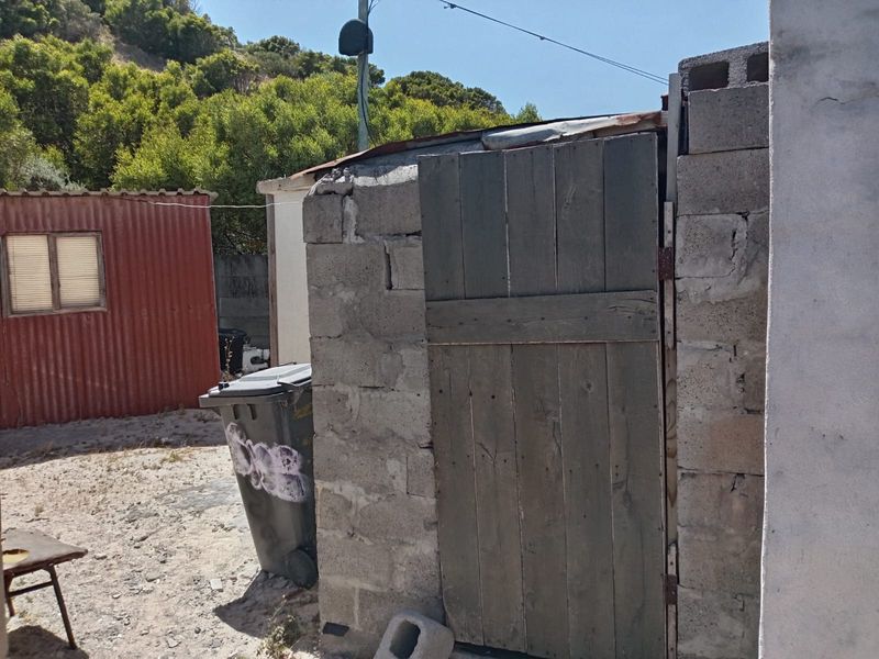 A basic utility structure constructed from cinder blocks and timber, showing significant signs of wear and unfinished exterior finishes.