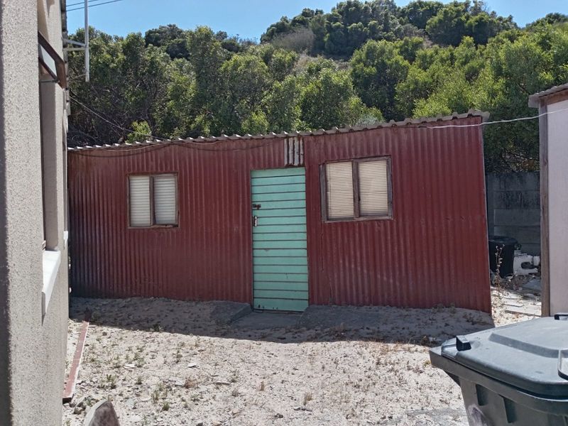 A detached corrugated iron structure located in the rear yard, showing significant signs of weathering and wear.