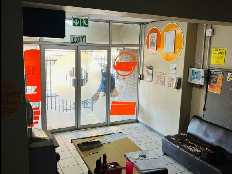 A functional building entrance area featuring glass doors, tiled flooring, and basic security intercom infrastructure.