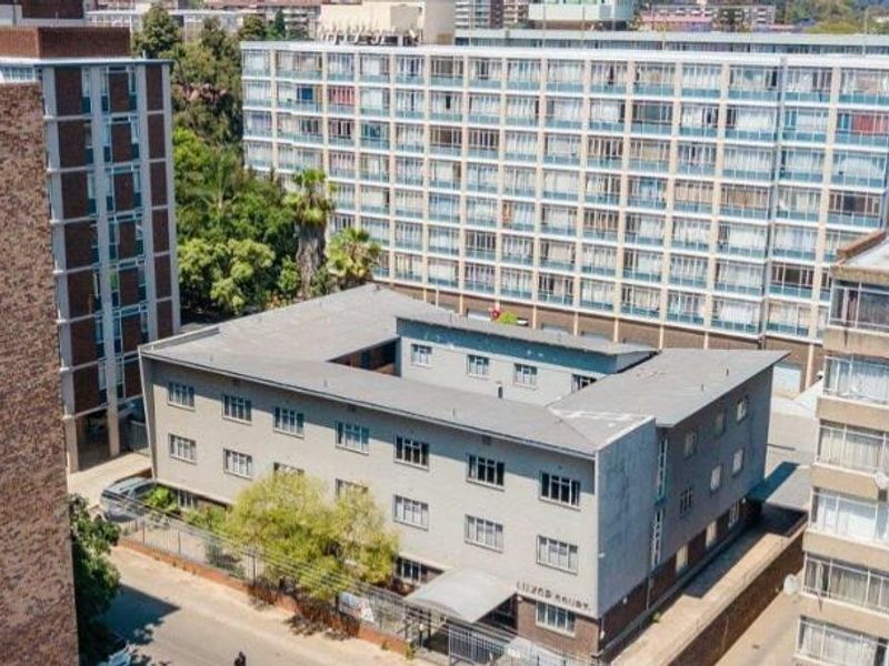 Aerial view of a multi-story apartment complex situated within a dense urban residential neighborhood.