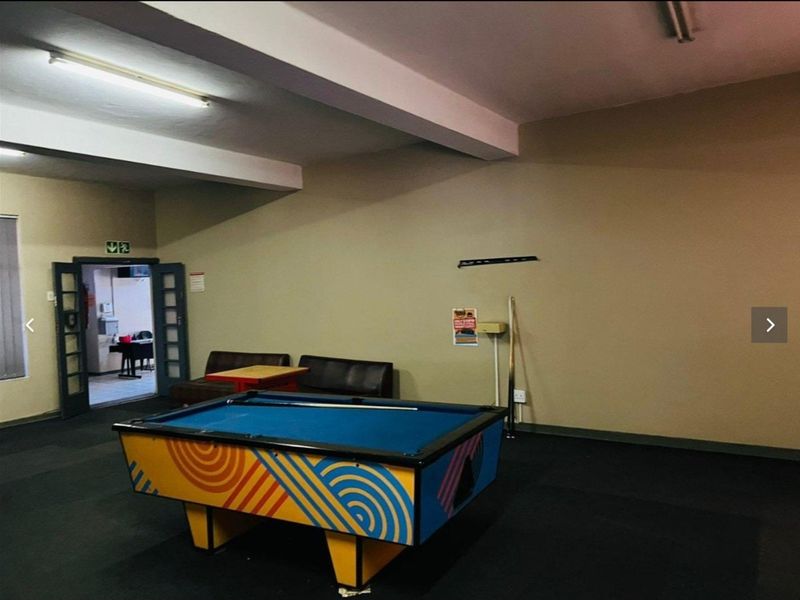 A spacious clubhouse area featuring carpeted flooring and fluorescent lighting, providing a versatile recreational space for residents.