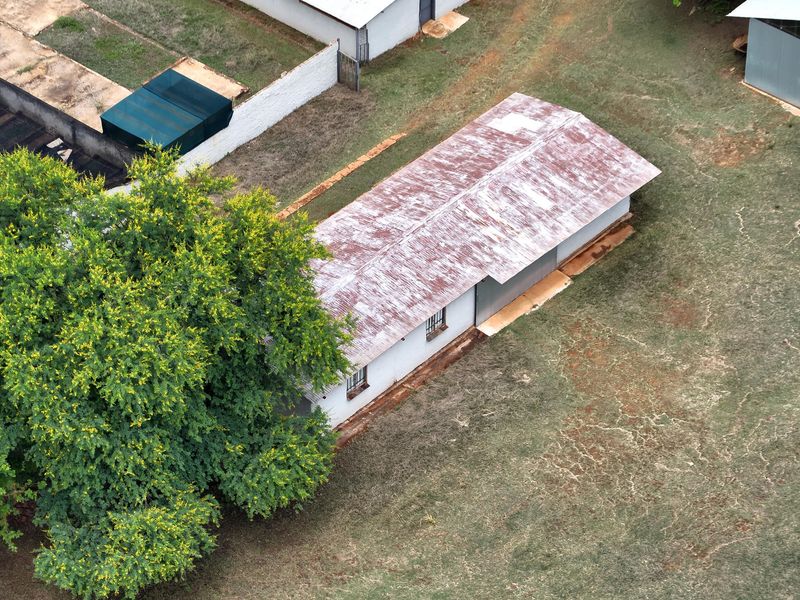 Aerial view of a farm outbuilding featuring a weathered corrugated metal roof and security bars on the windows.