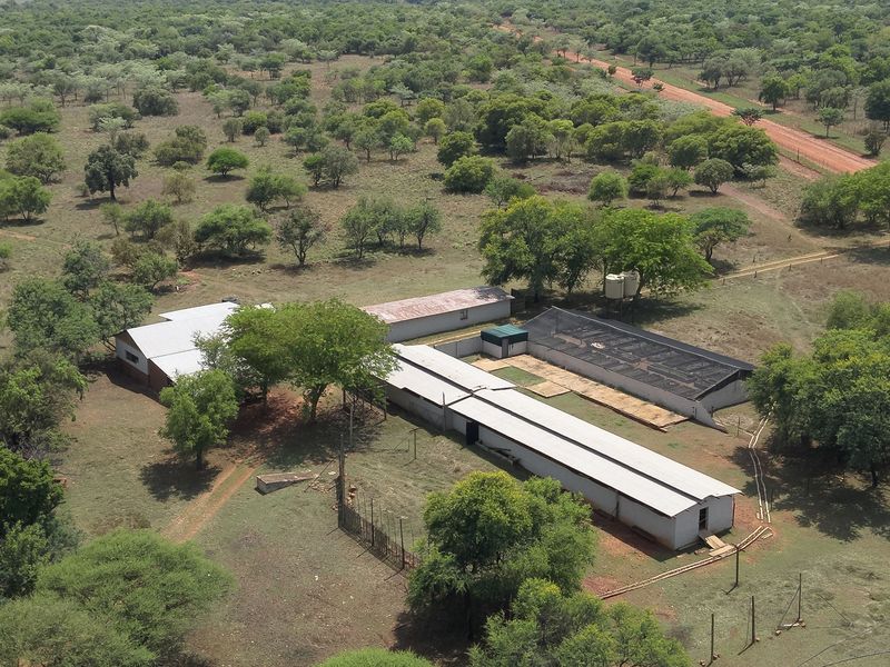 Aerial view of a farm property featuring multiple outbuildings with corrugated metal roofs, water storage tanks, and surrounding rural landscape.