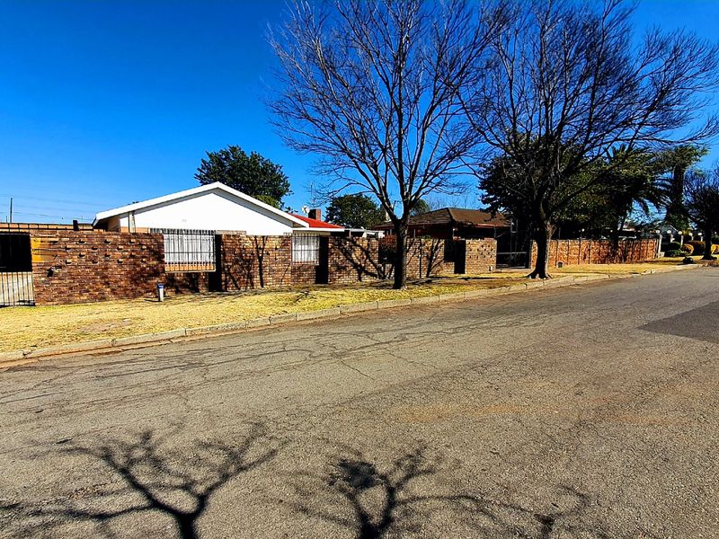 Street view of the property showing the brick boundary wall, security gate, and exterior facade of the house.