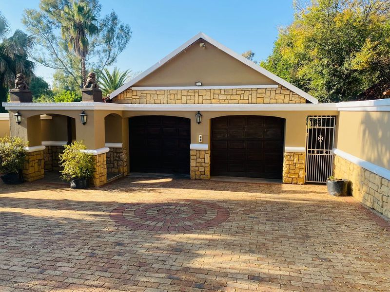 A well-maintained double garage featuring stone cladding accents, dark wood-finish doors, and a decorative circular brick-paved driveway.