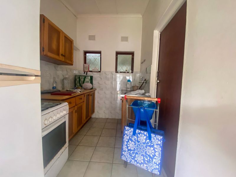 A functional scullery area featuring wooden cabinetry, tiled splashbacks, and tiled flooring, providing additional prep and utility space.